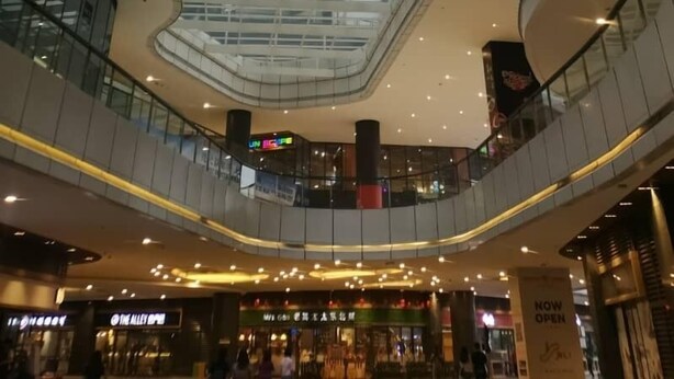 A modern shopping mall interior with high-rise buildings in the background, multiple levels, and various retail stores. - R&F Princess Cove by Wong (Johor Bahru)