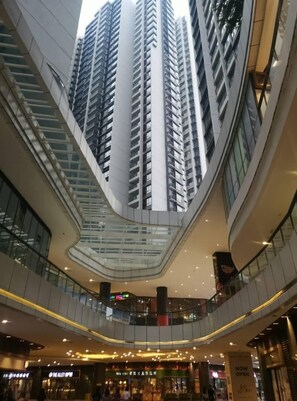 L’intérieur d’un centre commercial moderne, avec de grands immeubles en arrière-plan, plusieurs niveaux et divers magasins.