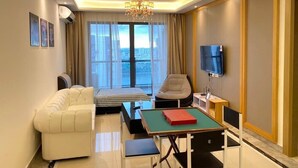 A modern hotel room with a bed, a sofa, a TV, and a table with a book. - R&F Princess Cove by Wong (Johor Bahru)