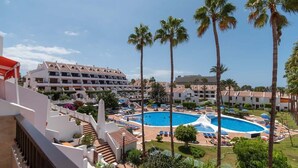 A hotel with a large pool surrounded by palm trees and sun loungers. - Parque Santiago II 178 - Two Bed (Playa de la Américas)