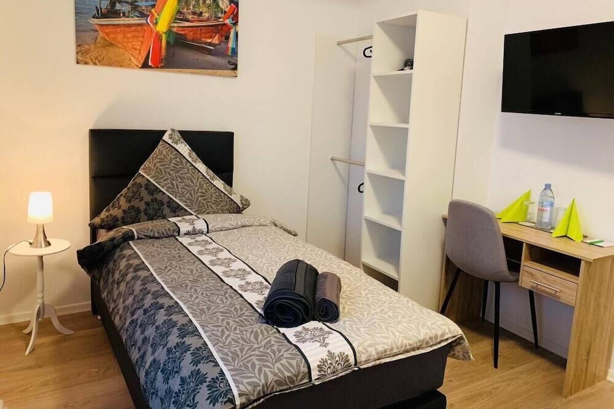 Une chambre d’hôtel bien aménagée, avec un lit, un bureau, une chaise, une télévision et une armoire.