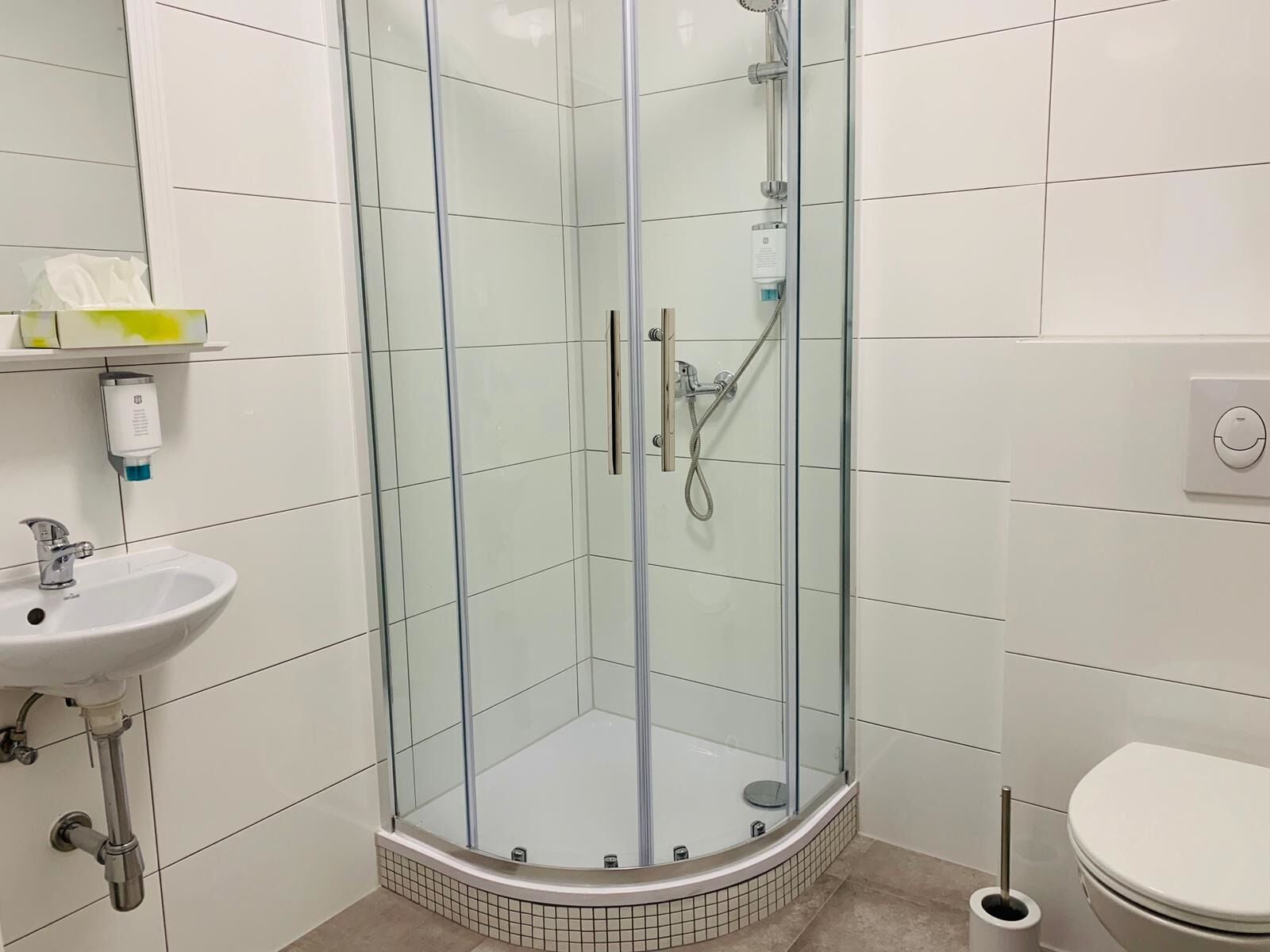 A modern bathroom with a glass-enclosed shower, a sink, and a toilet.