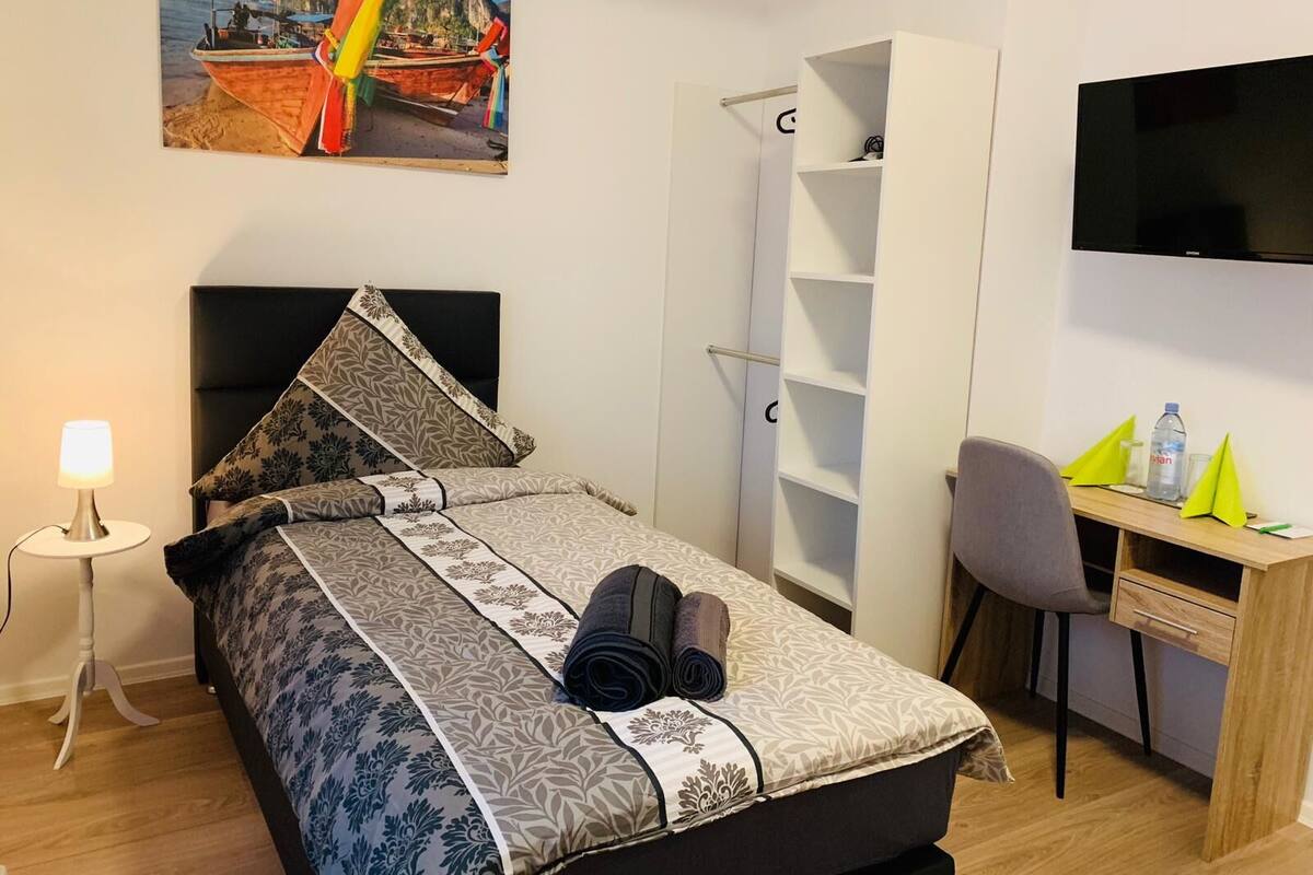 Une chambre d’hôtel comprenant un lit, un bureau, une chaise, une armoire et un téléviseur.