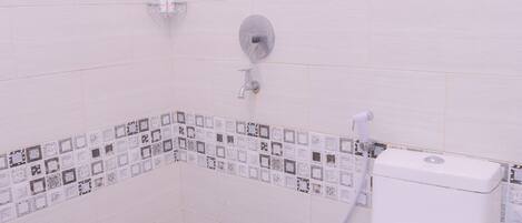 Un baño con inodoro, ducha y pared de azulejos con un borde decorativo.