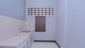 Une petite salle de bain propre, avec un lavabo blanc, un miroir et un panneau en bois au-dessus du miroir.