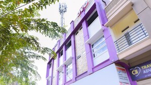 Un immeuble à plusieurs étages, doté d’une façade violette, d’une enseigne bien visible indiquant qu’il s’agit d’un magasin de produits pour bébés, et offrant une vue dégagée sur le ciel.