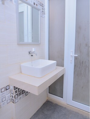 A bathroom with a white sink, a mirror, and a shower area.
