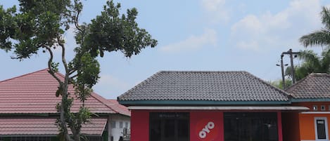 A building with a red and orange facade, a tiled roof, and a large window with the logo "oyo".