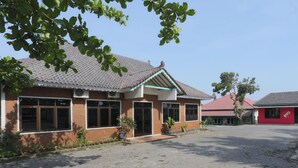A building with a tiled roof, large windows, and a paved courtyard. - Hotel O Penginapan Kepurun Pawana Indonesia (Cangkringan)