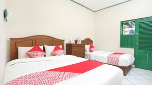 A hotel room with two beds, a wooden headboard, a green door, and a tiled floor. - Hotel O Penginapan Kepurun Pawana Indonesia (Cangkringan)