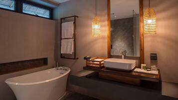Un baño moderno con una bañera independiente, un tocador con espejo y dos lámparas colgantes.