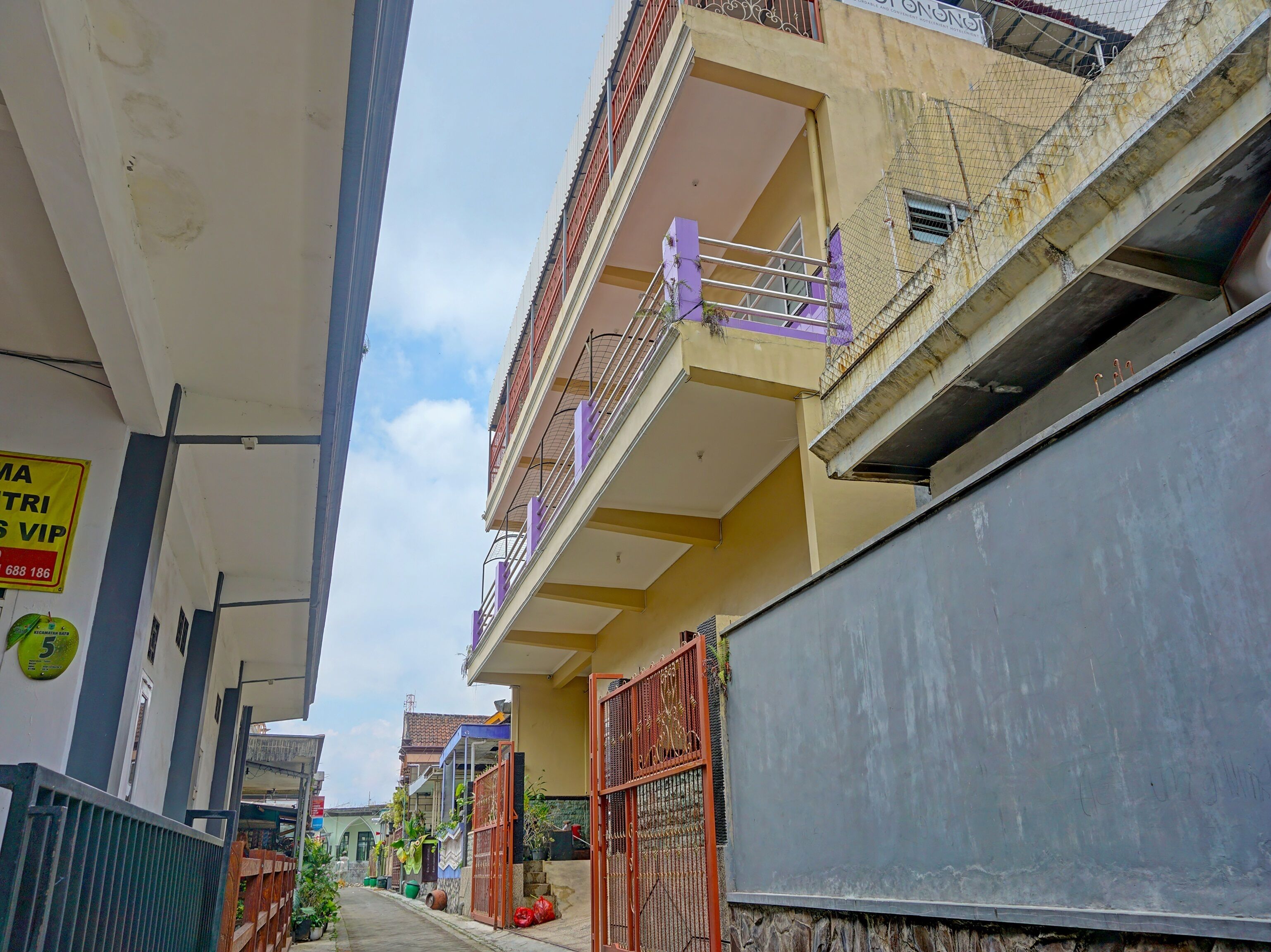 A narrow urban street with multi-story buildings, balconies, and a visible sign indicating a VIP service.