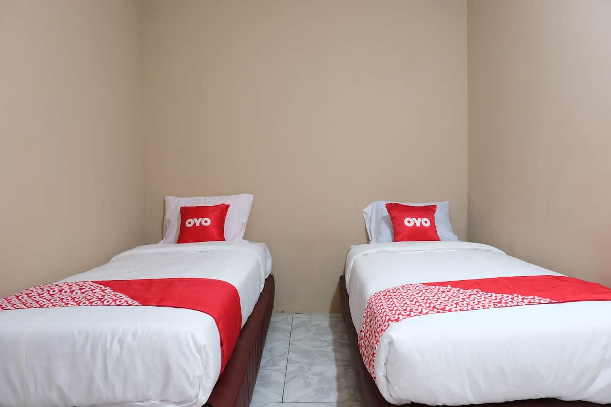 Two single beds with white and red bedding, each with a pillow labeled "OYO".