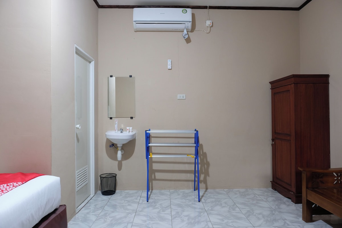 Une salle de bain équipée d’un lit, d’un lavabo, d’un miroir, d’un climatiseur et d’une armoire en bois.