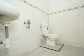 A bathroom with white tiles, a toilet, a sink, and a pipe.