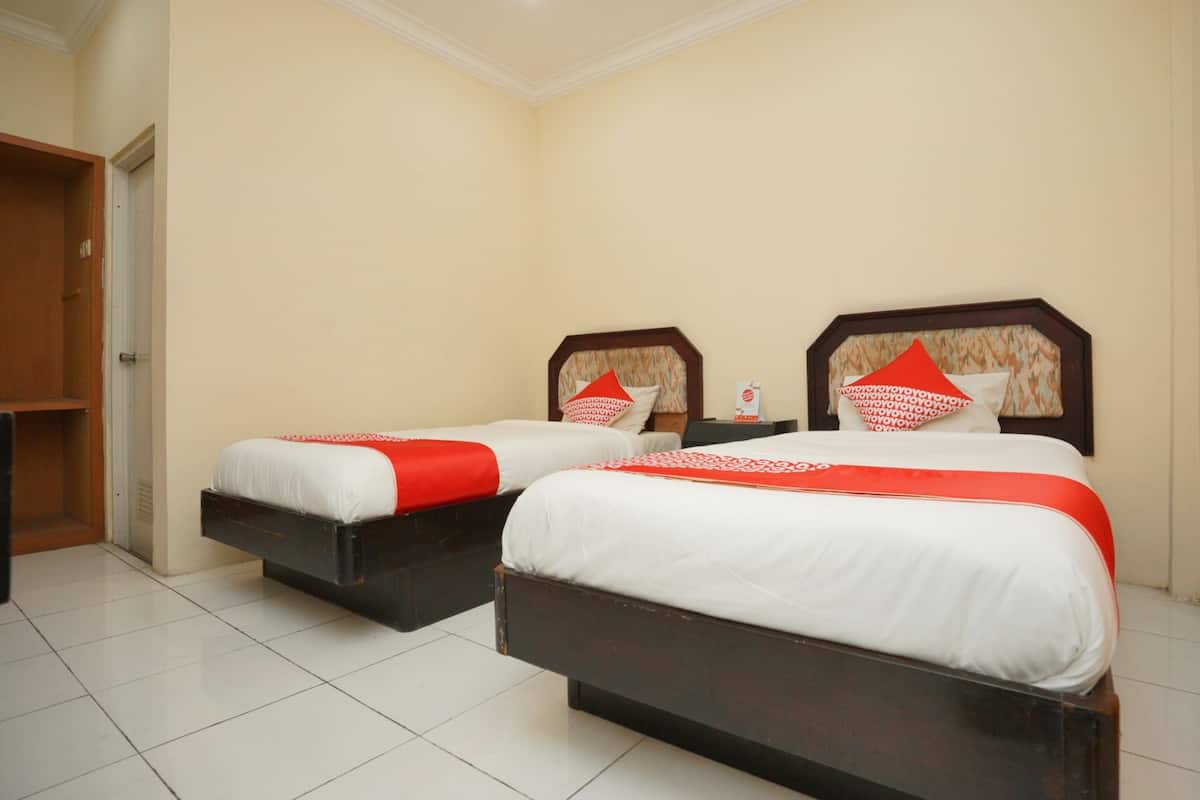 Two beds with white and red bedding, wooden headboards, and a tiled floor.