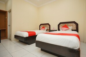 Two beds with white and red bedding, wooden headboards, and a tiled floor.