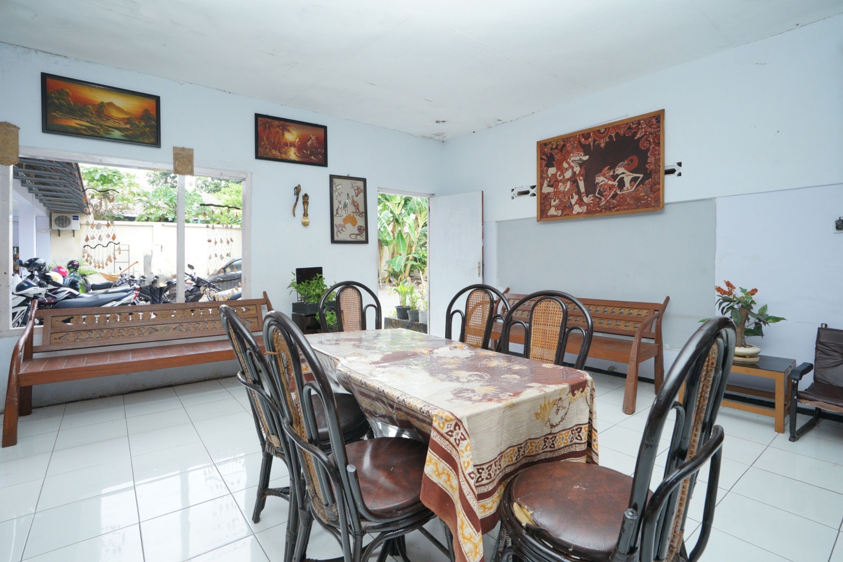 A dining area with a table, chairs, benches, and artwork on the walls.