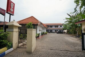 A gated entrance to a building with a tiled roof, potted plants, and a clear sky.