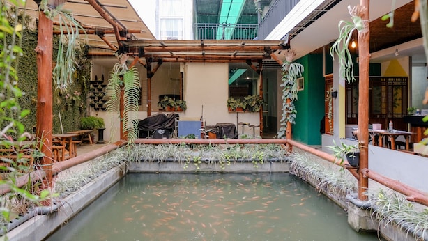A courtyard with a koi pond, bamboo structures, and potted plants. - OYO 1622 Kakap 88 Family Homestay (Malang)