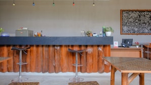 A bar area with a wooden counter, stools, and a chalkboard with cooking and beverage illustrations. - OYO 1622 Kakap 88 Family Homestay (Malang)