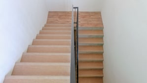 A wooden staircase with a metal handrail, leading up to a landing. - OYO 1622 Kakap 88 Family Homestay (Malang)