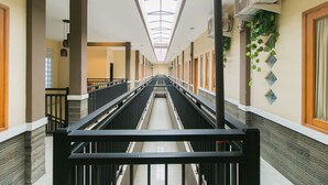 Un long couloir étroit, avec une allée centrale, bordé de murs recouverts de carreaux décoratifs et surmonté d’un plafond doté de lucarnes.