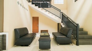 Un vaste espace de vie comprenant un escalier, deux canapés en cuir, une table basse et une porte en bois.