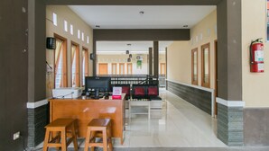 Un hall d’hôtel comprenant un comptoir d’accueil, un espace salon et un extincteur fixé au mur.