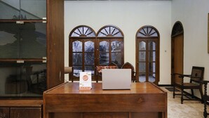 A wooden reception desk with a laptop, a sign, and a chair. - Hotel O Penginapan Bidara Syariah (Probolinggo)