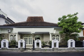 A two-story house with a tiled roof, white walls, and a stone foundation.
