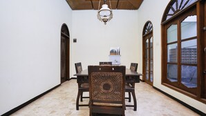 A dining area with a wooden table and chairs, a chandelier, and a large window with a view. - Hotel O Penginapan Bidara Syariah (Probolinggo)