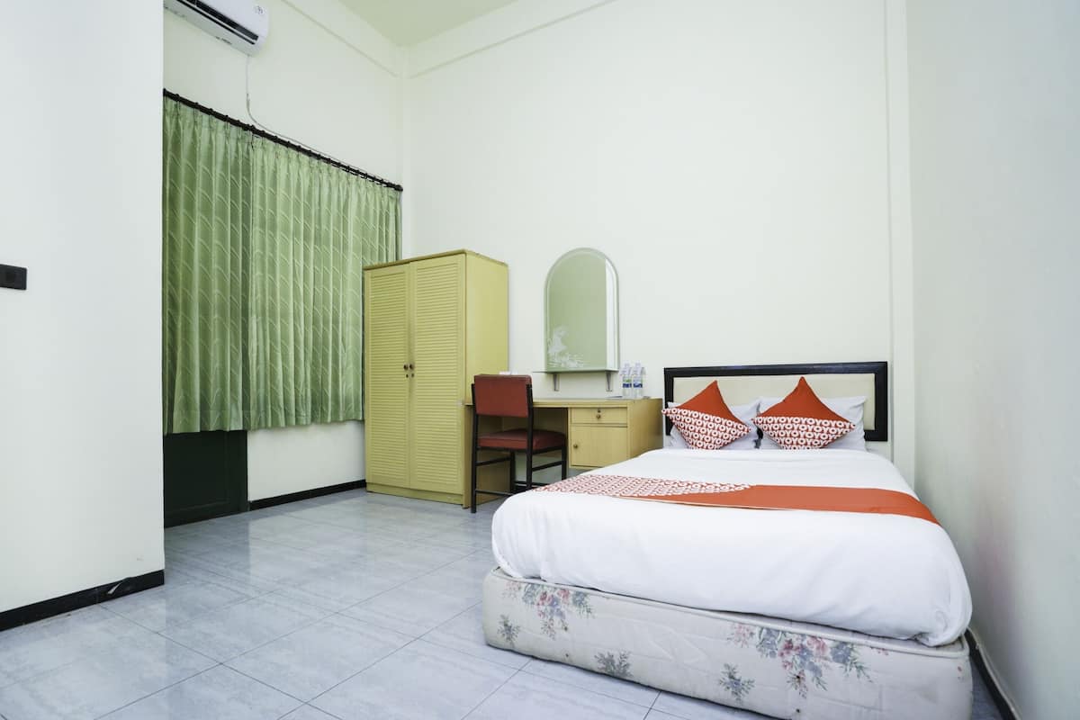 A hotel room with a bed, a desk, a chair, a wardrobe, and a mirror.