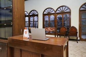 A wooden desk with a laptop, a brochure, and a window with a view of mountains.