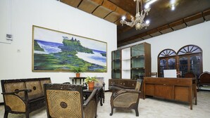 A room with a large landscape painting, wooden furniture, and a chandelier. - Hotel O Penginapan Bidara Syariah (Probolinggo)