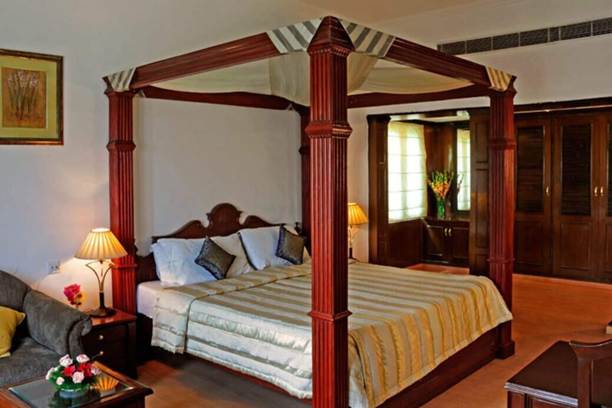Ein Bett mit Himmelbett, ein Nachttisch mit Lampe, ein Beistelltisch, eine Couch und ein gerahmtes Bild an der Wand.