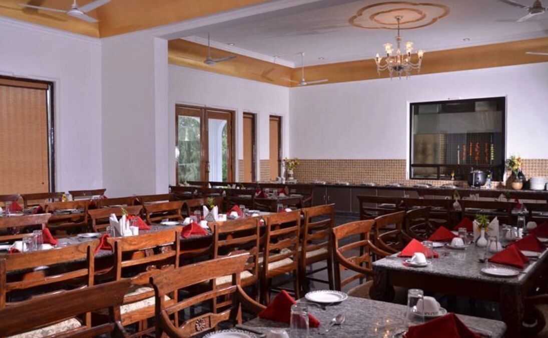 A dining area with wooden tables and chairs, a chandelier, and a large window.
