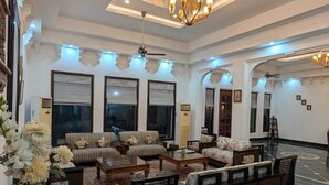 A spacious living area with a high ceiling, modern furniture, and a decorative chandelier.