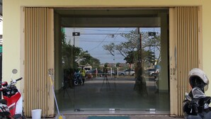 A building entrance with a glass door, a parked motorcycle, and a tripod in the foreground. - Hotel O Pondok Bintang (Somba Opu)