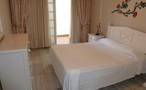 Quarto com cama, mesa de cabeceira e cômoda.