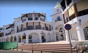 Um edifício branco com várias varandas e uma torre do relógio.
