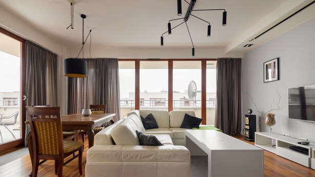 A modern living room with a sofa, dining table, and TV. - Hlonda Deluxe Apartment with Terrace (Warsaw)