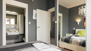 A modern bedroom with a bed, bedside table, and a bathroom visible through an open door. - Hlonda Deluxe Apartment with Terrace (Warsaw)