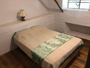 Une petite pièce simple, avec un lit, une lampe et une fenêtre.