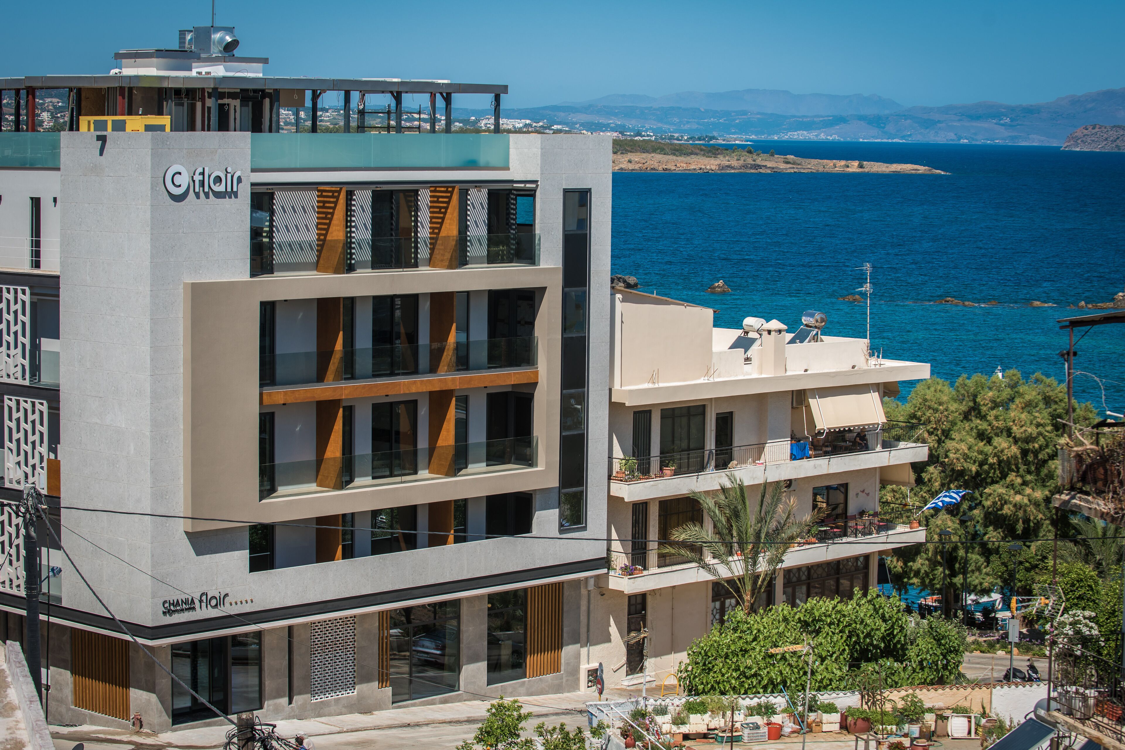 A modern hotel with multiple floors, large windows, and balconies overlooking a coastal area.