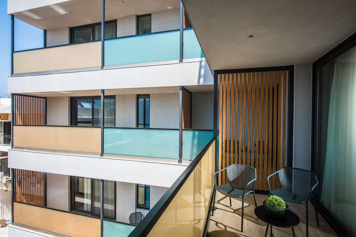 Un edificio de varios pisos con balcones, barandillas de vidrio y muebles modernos.