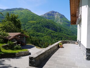 Ein gepflasterter Weg führt zu einem Gebäude mit Blick auf üppige, grüne Berge.