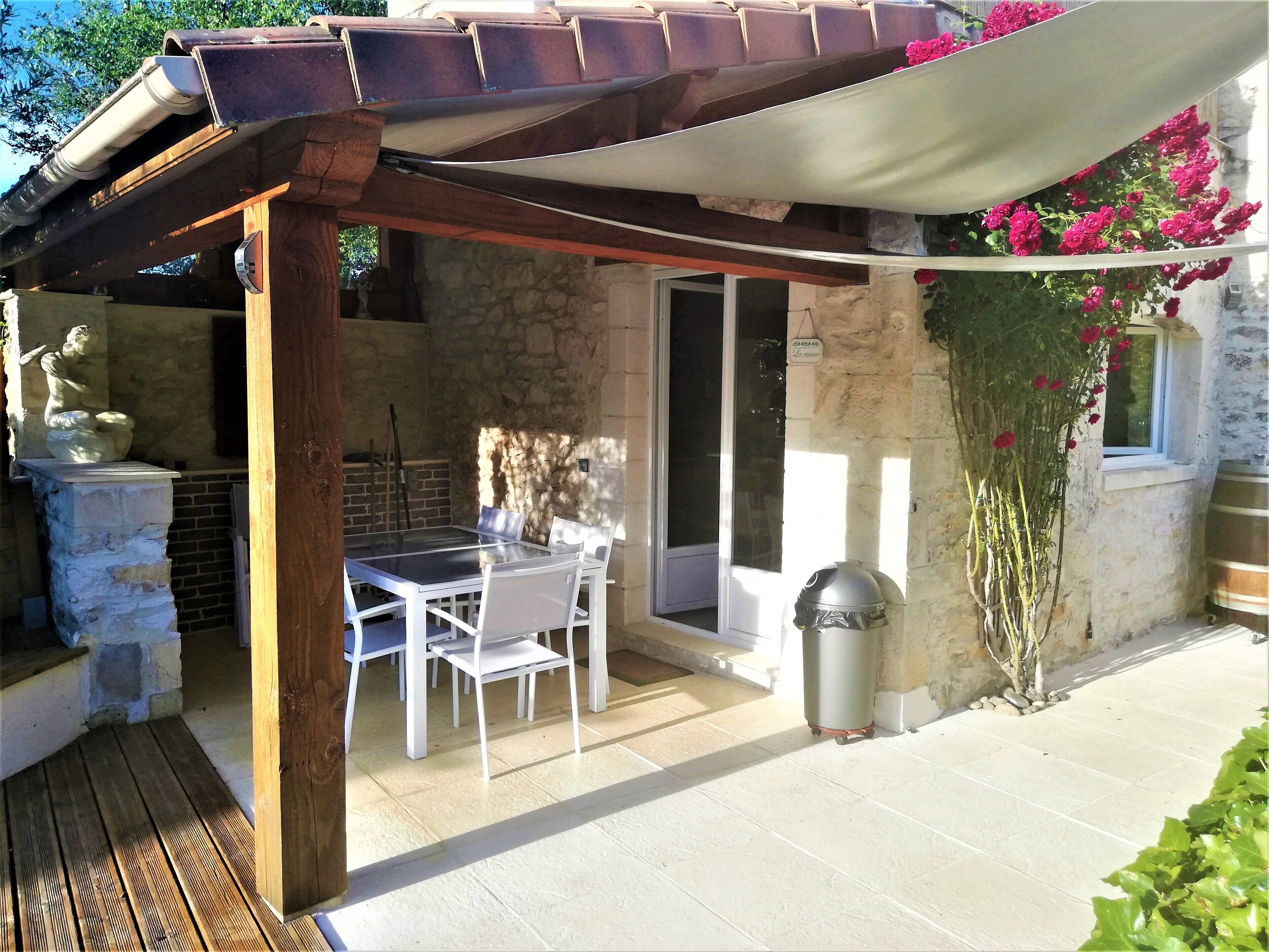 A patio with a table and chairs, a stone wall, a statue, and a grill.