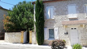 A stone building with a tiled roof, a small window with shutters, and a door.