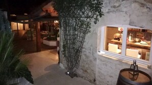 A rustic building with a stone exterior, a window with a view of the interior, and a barrel outside.